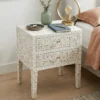 White mother of pearl nightstand with personal items in bedroom