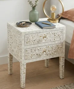 White mother of pearl nightstand with personal items in bedroom