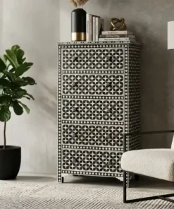 Black bone inlay 5 drawer tall chest of drawers placed in modern living room with white chair and plant