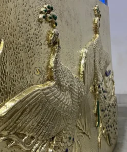 Detailed view of brass embossed peacock design with gemstone inlays