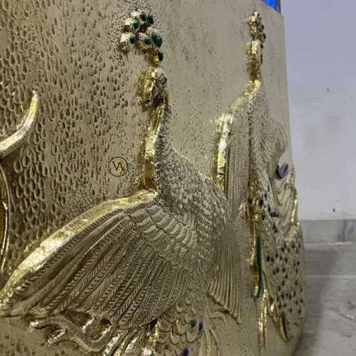 Detailed view of brass embossed peacock design with gemstone inlays