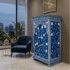 Navy blue mother of pearl small storage cabinet with floral inlay design and double doors placed in modern suite room with blue chair and wall decor
