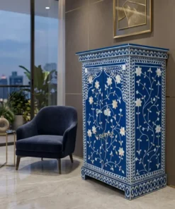 Navy blue mother of pearl small storage cabinet with floral inlay design and double doors placed in modern suite room with blue chair and wall decor