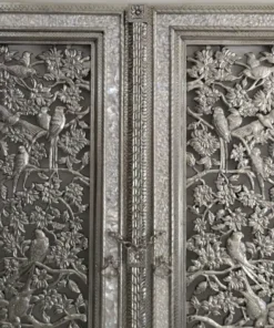 Detailed bird and flower carvings on a decorative silver-toned temple door